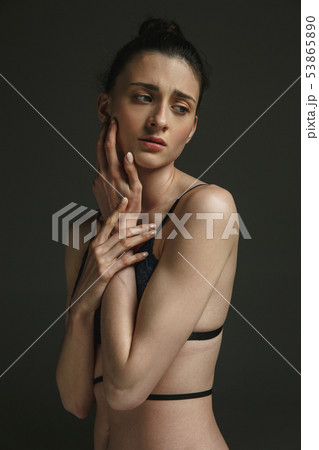 Half-length portrait of young sad woman on dark studio background 53865890