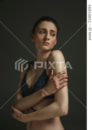 Half-length portrait of young sad woman on dark studio background Half-length portrait of young sad woman on dark studio background 53865893