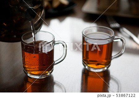 Black hot tea to glass mugs. Selective focus. Close up. 53867122
