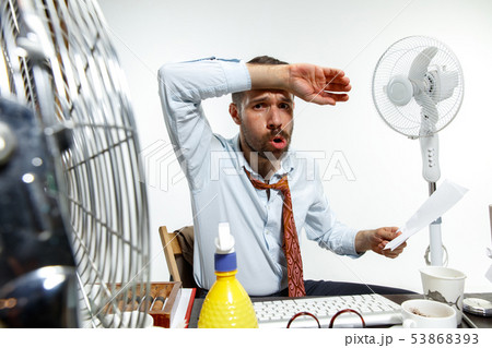Young man ssuffering from the heat in the office Young man ssuffering from the heat in the office 53868393
