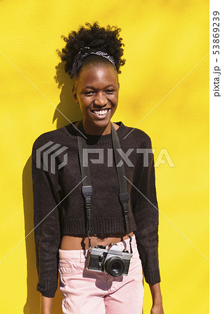 Young black woman in sweater and jeans with camera 53869239