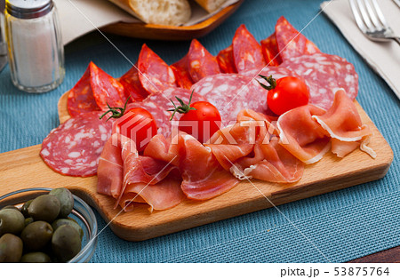 Spanish tasty meal slicing sausages and jamon with tomatoes, close up 53875764