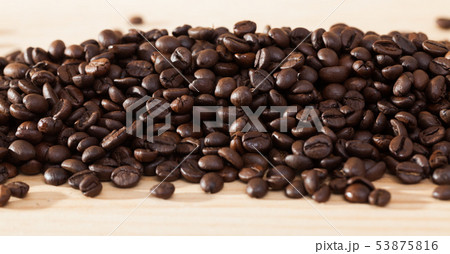 Coffee beans on light wood surface Coffee beans on light wood surface 53875816