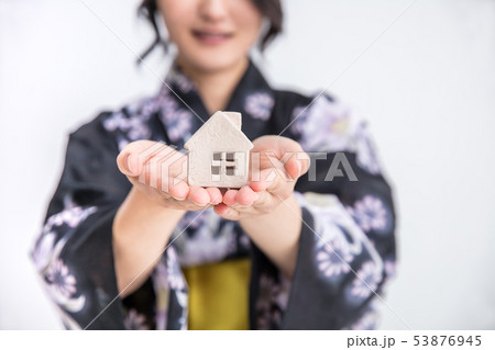 浴衣を着た30代のきれいな女性が白背景で家の模型をもっているの写真素材
