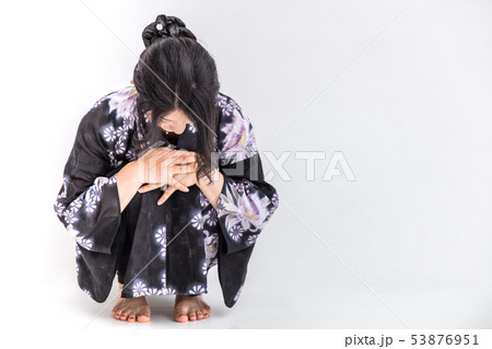浴衣を着た30代のきれいな女性が白背景でうずくまるの写真素材