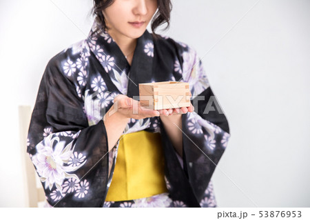 浴衣を着た30代のきれいな女性が白背景で升で日本酒を飲んでいるの写真素材