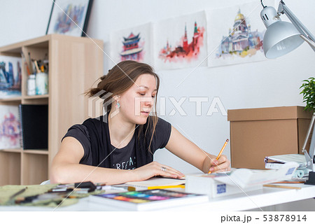 Young female artist drawing sketch using sketchbook with pencil at her workplace in studio. Side Young female artist drawing sketch using sketchbook with pencil at her workplace in studio. Side 53878914