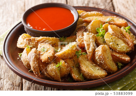Hot potato wedges with parmesan cheese and oregano Hot potato wedges with parmesan cheese and oregano 53883099