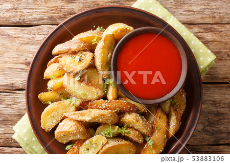 Hot potato wedges with parmesan cheese and oregano Hot potato wedges with parmesan cheese and oregano 53883106