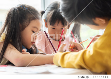 Asian little kids are colouring in a classroom. 53886311