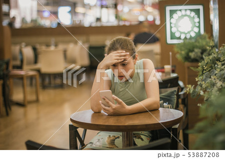 Young girl is crying along in a cafe closing her Young girl is crying along in a cafe closing her 53887208