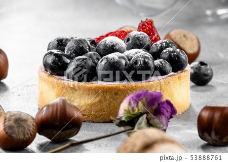 Blueberry and strawberry shortcake. There are hazelnuts, roses and wine corks on the table. Stone Blueberry and strawberry shortcake. There are hazelnuts, roses and wine corks on the table. Stone 53888761