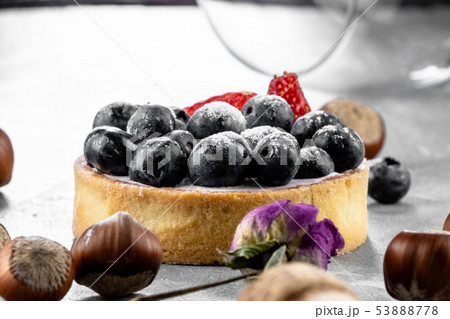 Blueberry and strawberry shortcake. There are hazelnuts, roses and wine corks on the table. Stone 53888778
