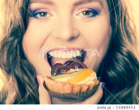 Closeup woman face and fruit cake Closeup woman face and fruit cake 53889453