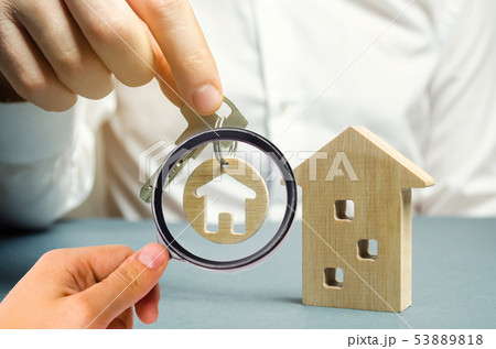 A man holds a trinket key with a house 53889818