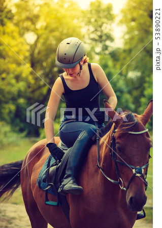 Jockey young woman getting horse ready for ride 53890221