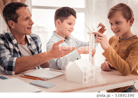 Foster father wearing square shirt teaching his adopted children 53891390