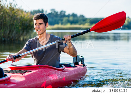 Man sitting in kayak paddling on lake 53898135