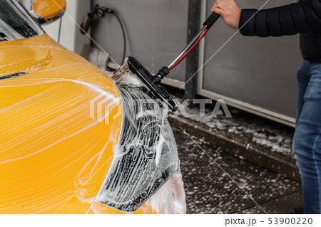 Man cleaning his car in self serve carwash, brush Man cleaning his car in self serve carwash, brush 53900220