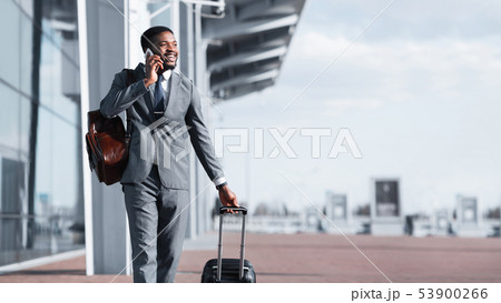 Afro Businessman Walking With Luggage And Talking On Phone 53900266