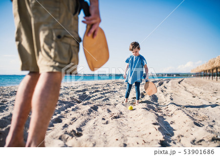 A small girl with unrecognizable father playing outdoors on sand beach. A small girl with unrecognizable father playing outdoors on sand beach. 53901686