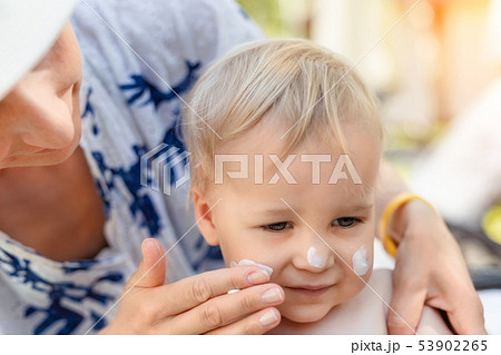 Mother applying sunscreen protection creme on cute little toddler boy face. Mom using sunblocking 53902265