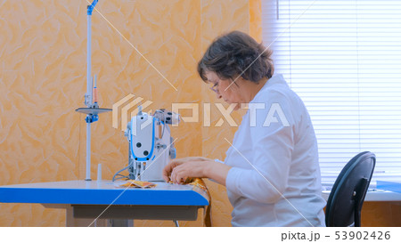 Woman designer sewing clothes with sewing machine at atelier Woman designer sewing clothes with sewing machine at atelier 53902426