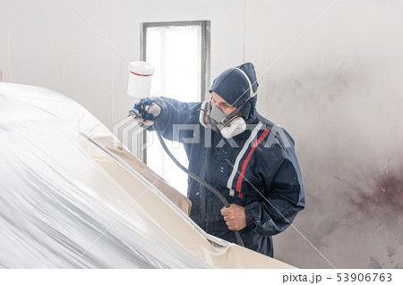 Car service station. Worker painting a white car in special garage, wearing costume and protective 53906763