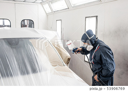 Car service station. Worker painting a white car in special garage, wearing costume and protective 53906769