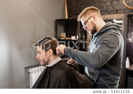 Barber work with clipper machine in barbershop. Professional trimmer tool cuts beard and hair on 53911226
