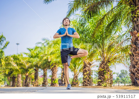 Man doing yoga in a tropical park 53911517