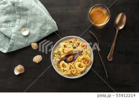 Seafood pasta. Tagliolini with mussels, shrimps, clams and squid rings, with a glass of white wine 53912214