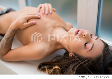 Naked attractive woman lying down on windowsill 53912559