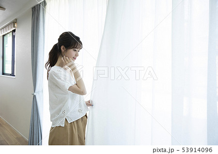 カーテンの側に立つ若い女性 53914096