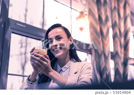 Delighted happy woman giving holding a glass of juice Delighted happy woman giving holding a glass of juice 53914804