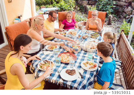 Family having a garden party eating at the table Family having a garden party eating at the table 53915031