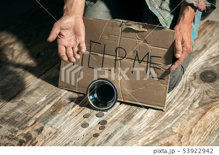 Male beggar hands seeking money on the wooden floor at public path way 53922942