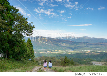 遠くの山を見つめる子供達の写真素材