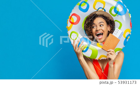 Excited millennial black woman holding swim ring and tickets for travel 53931173