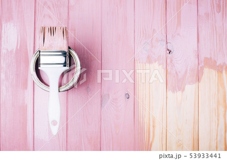 White brush on open can of pink color on painting wooden board. 53933441