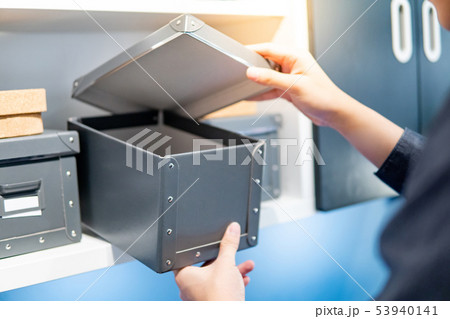Male hand opening gray paper box on shelf 53940141