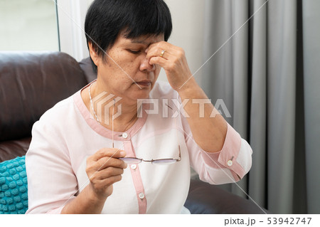 Tired old woman removing eyeglasses, massaging Tired old woman removing eyeglasses, massaging 53942747