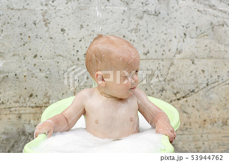 Funny cute bay boy taking a bath outdoor. Funny toddler in a soapy foam. 53944762