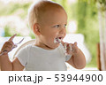 Cute funny little blonde toddler boy eating delicious yogurt sitting outdoor 53944900