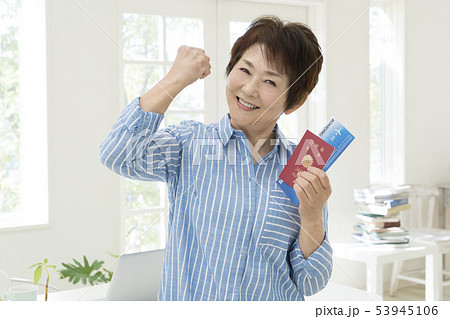 パスポートと旅券を持ってガッツポーズをするシニア女性 53945106