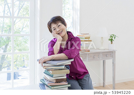 積み重ねた本の上で頬杖をつく眼鏡のシニア女性 積み重ねた本の上で頬杖をつく眼鏡のシニア女性 53945220