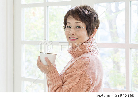 マグカップを持って振り返る眼鏡のシニア女性 マグカップを持って振り返る眼鏡のシニア女性 53945269