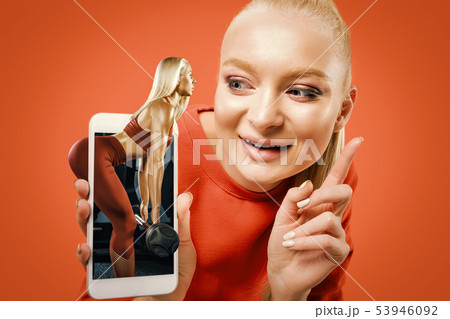 Portrait of woman showing screen of mobile phone isolated over orange background 53946092
