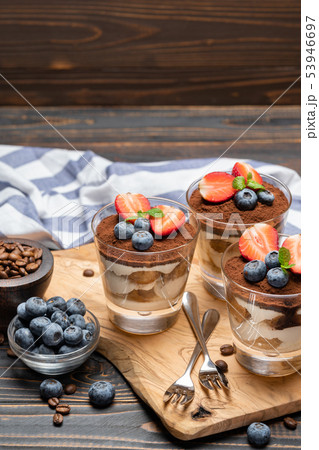 Classic tiramisu dessert with blueberries and strawberries in a glass on wooden background 53946697