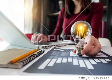 Lady using tabtop and holding light bulb,with idea Lady using tabtop and holding light bulb,with idea 53949417